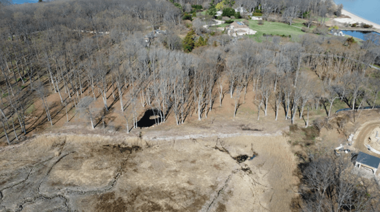 Drone aerial showing cleared land and log wall pushed into wetland, April 2026
